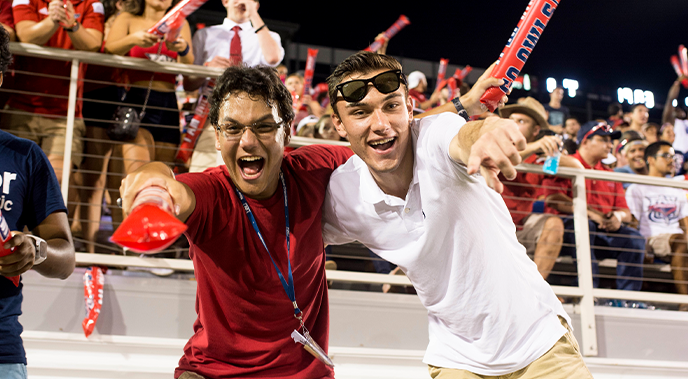 Two male 啵啵直播秀 during an FAU football game smiling and pointing at the camera