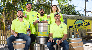 Five people posing with beer kegs in front of the Islamorada Beer Company sign